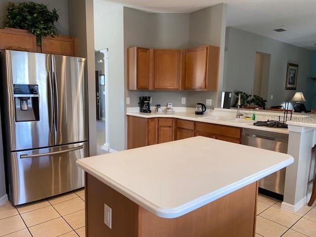 kitchen with appliances with stainless steel finishes, light tile patterned floors, and a kitchen island