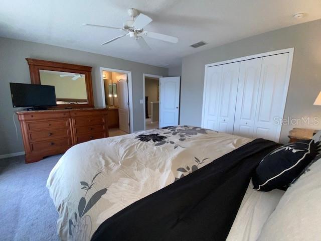 carpeted bedroom with ceiling fan and a closet