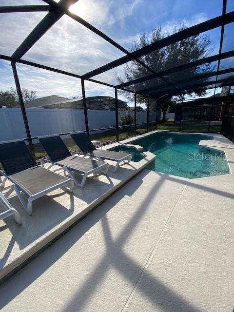 view of swimming pool featuring a patio and glass enclosure