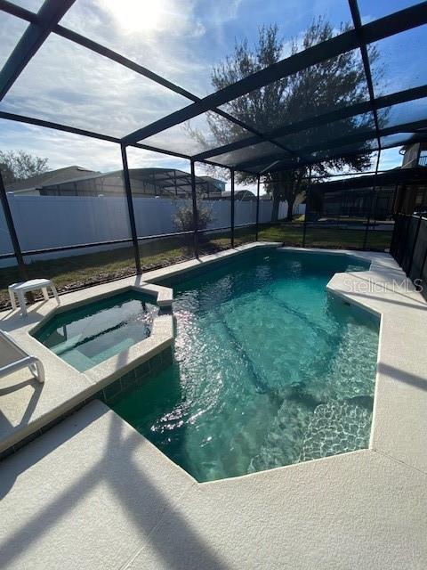 view of swimming pool featuring a patio area, a lanai, and an in ground hot tub