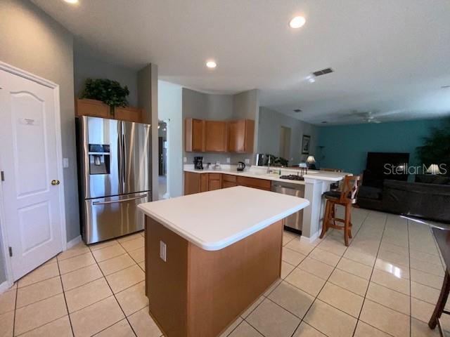 kitchen with a center island, kitchen peninsula, stainless steel appliances, and light tile patterned floors