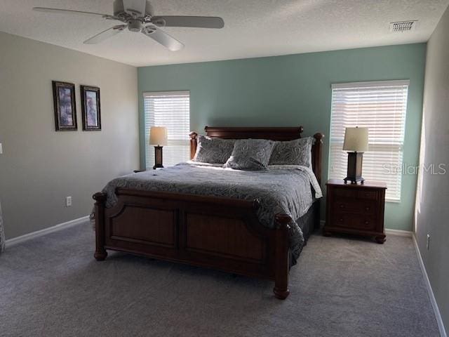 bedroom featuring ceiling fan, dark carpet, and multiple windows