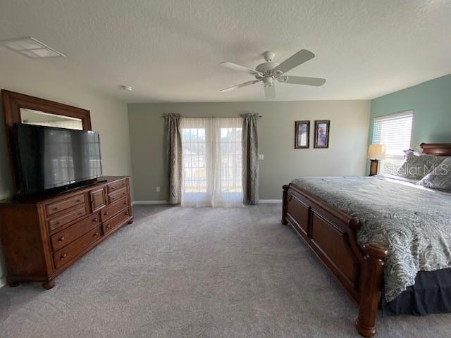 bedroom featuring a textured ceiling, light colored carpet, and ceiling fan