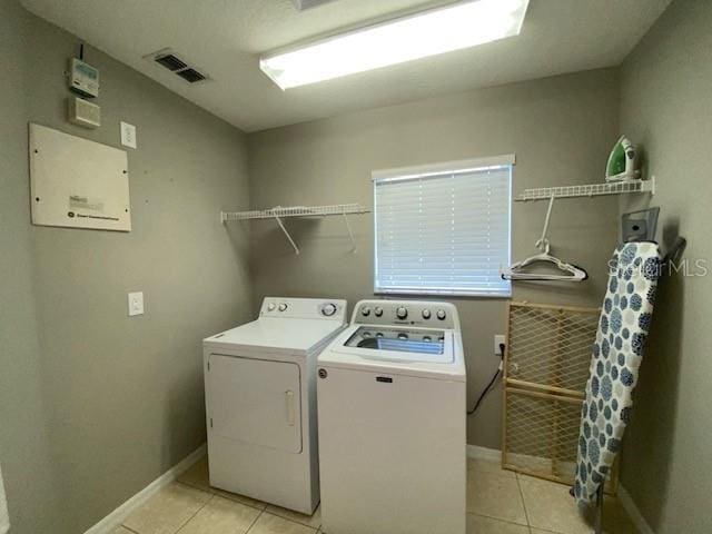 laundry area with washer and clothes dryer and light tile patterned floors