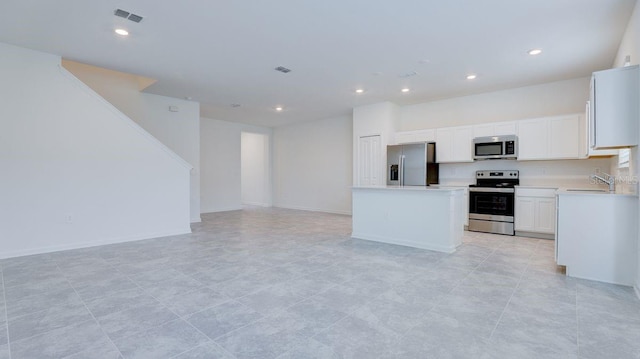 kitchen featuring appliances with stainless steel finishes, a kitchen island, sink, light tile patterned floors, and white cabinetry