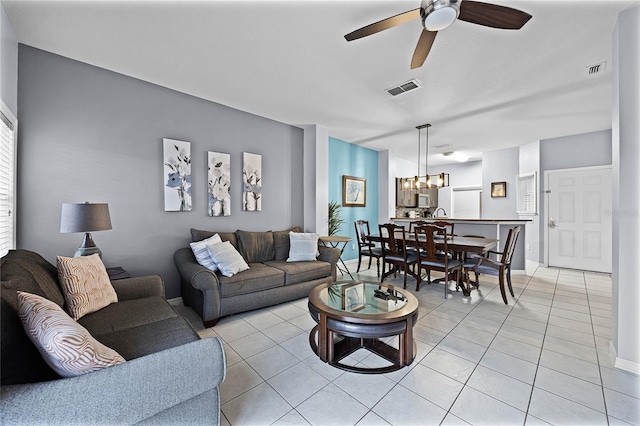 living room with light tile patterned floors and ceiling fan with notable chandelier