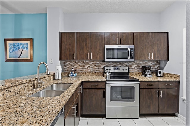 kitchen featuring dark brown cabinetry, light stone counters, and appliances with stainless steel finishes