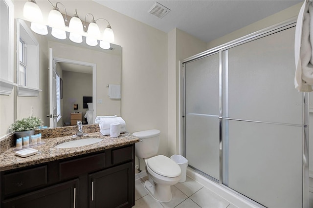 bathroom featuring tile patterned flooring, vanity, toilet, and a shower with door