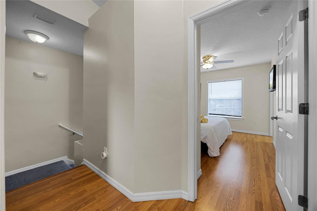 hall with hardwood / wood-style floors and a textured ceiling