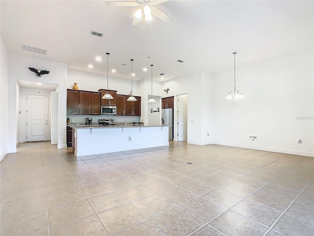 kitchen featuring pendant lighting, a breakfast bar area, appliances with stainless steel finishes, and an island with sink