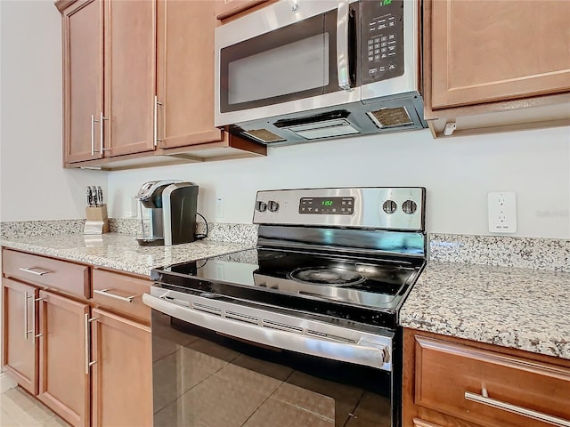 kitchen featuring light stone countertops, light tile patterned floors, and stainless steel appliances