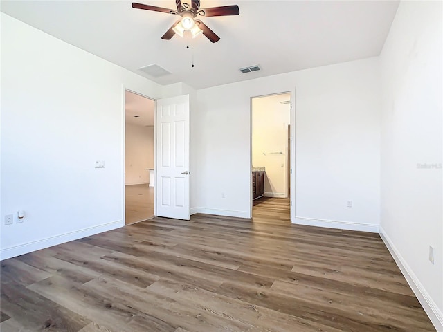 unfurnished bedroom featuring connected bathroom, dark hardwood / wood-style floors, and ceiling fan