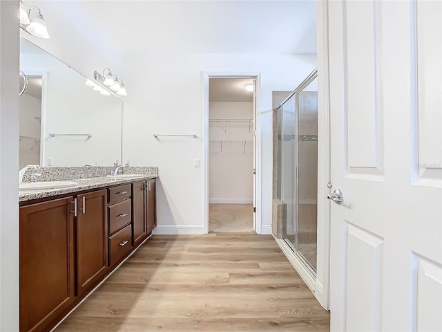 bathroom featuring hardwood / wood-style floors, vanity, and a shower with door