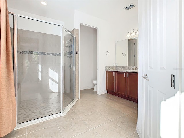 bathroom featuring tile patterned flooring, vanity, toilet, and a shower with shower door