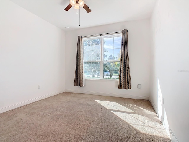 spare room with a wealth of natural light, ceiling fan, and light colored carpet