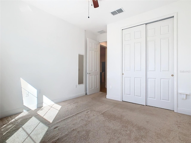 unfurnished bedroom with ceiling fan, light carpet, and a closet