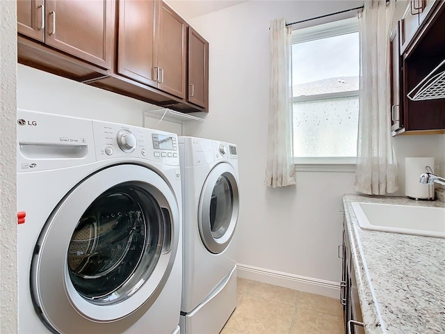 laundry room featuring cabinets, light tile patterned flooring, washer and clothes dryer, and sink