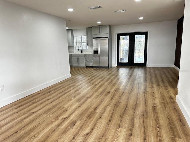 unfurnished living room with french doors, light hardwood / wood-style flooring, a wealth of natural light, and sink