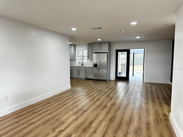 unfurnished living room featuring sink and light hardwood / wood-style flooring