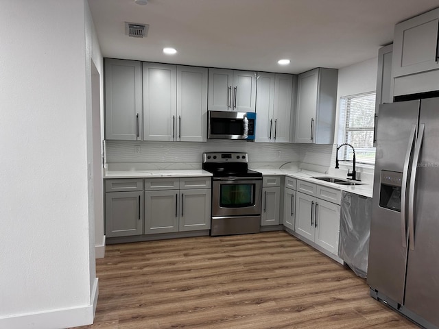 kitchen with appliances with stainless steel finishes, gray cabinets, and sink