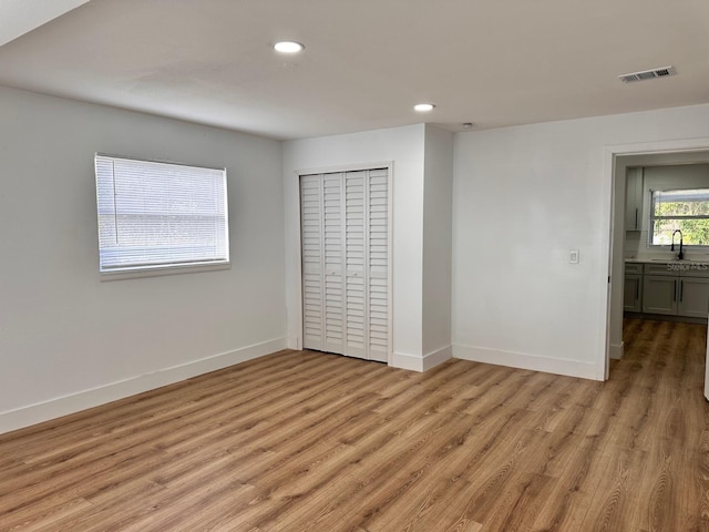 unfurnished bedroom featuring light hardwood / wood-style floors, sink, and a closet