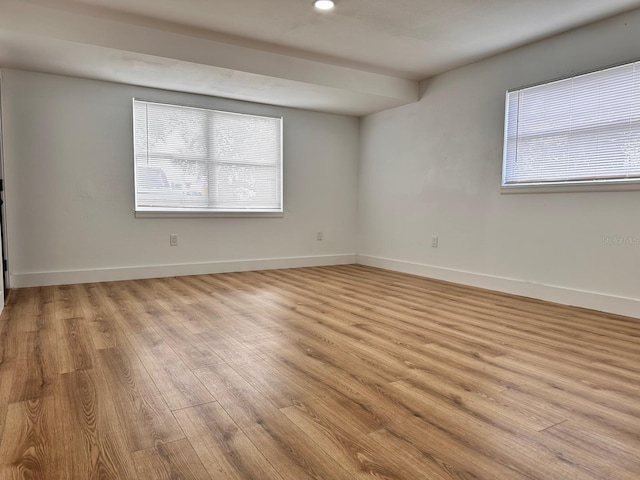 empty room with light hardwood / wood-style floors and plenty of natural light