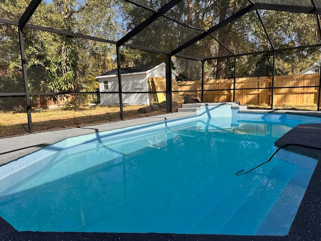 view of pool featuring glass enclosure and a shed