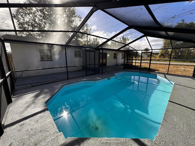 view of swimming pool featuring glass enclosure and a patio area