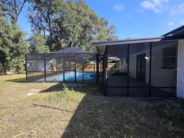 view of yard featuring a fenced in pool, glass enclosure, and a patio