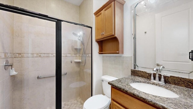 bathroom featuring tasteful backsplash, toilet, a shower with door, vanity, and tile walls