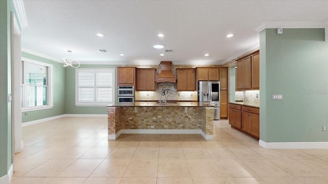 kitchen featuring custom range hood, stainless steel appliances, a kitchen island with sink, and crown molding