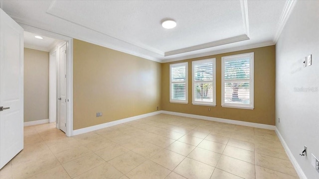 tiled empty room with a tray ceiling and crown molding