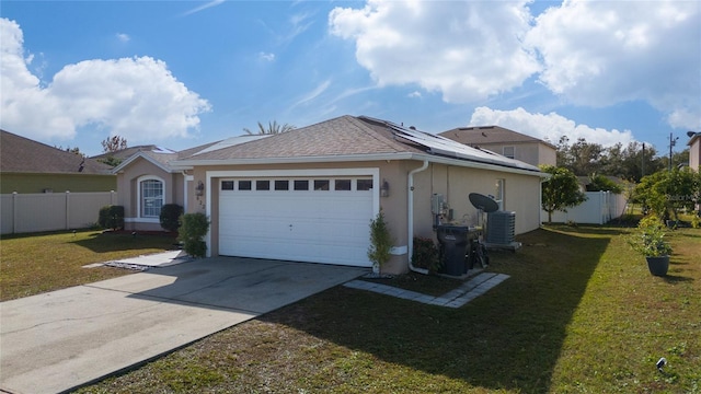 view of front of home featuring central AC, a garage, a front yard, and solar panels