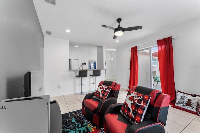 living room featuring ceiling fan, light tile patterned floors, and a textured ceiling