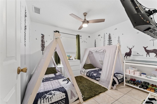 bedroom featuring ceiling fan, light tile patterned flooring, and a textured ceiling