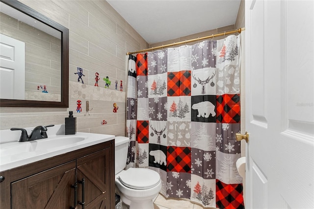 bathroom with vanity, toilet, and tile walls