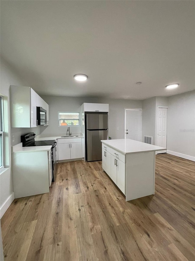 kitchen with white cabinetry, sink, appliances with stainless steel finishes, and light hardwood / wood-style flooring