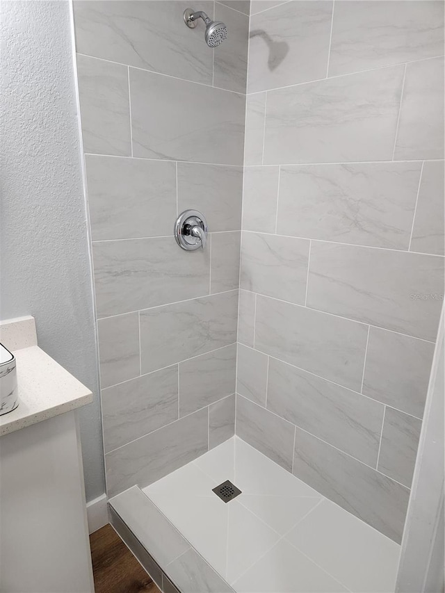 bathroom featuring hardwood / wood-style floors and a tile shower