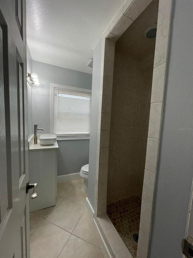 bathroom with tile patterned flooring, tiled shower, toilet, and sink