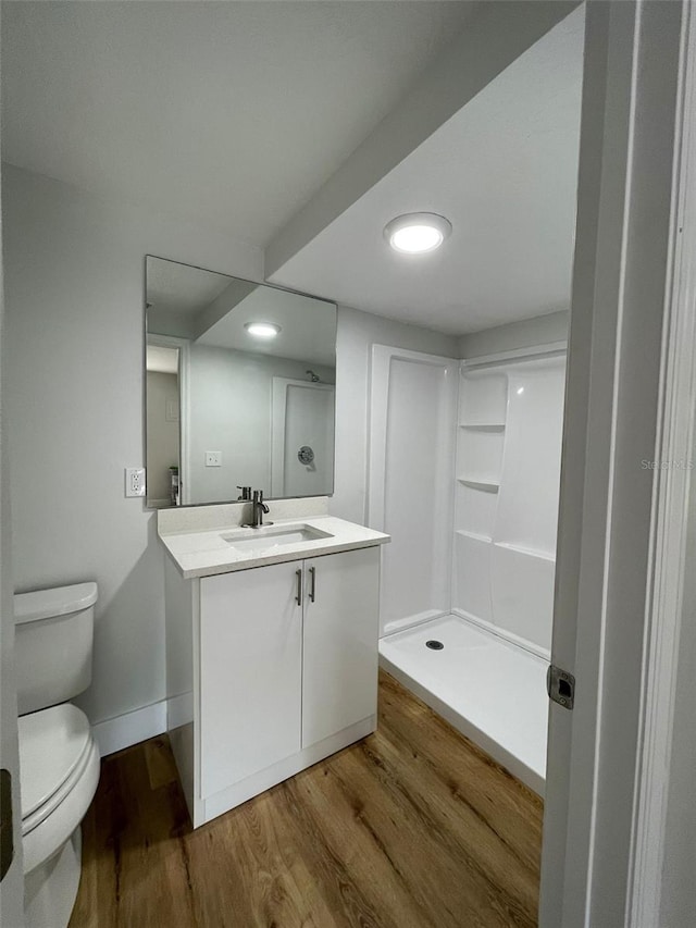 bathroom with walk in shower, hardwood / wood-style floors, vanity, and toilet