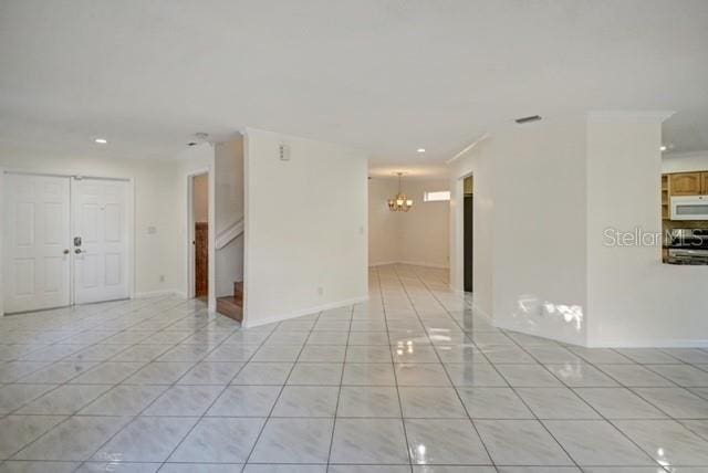 tiled empty room featuring an inviting chandelier