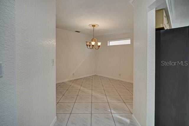 empty room featuring light tile patterned flooring and a notable chandelier