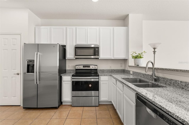 kitchen featuring sink, light tile patterned floors, light stone counters, white cabinetry, and stainless steel appliances