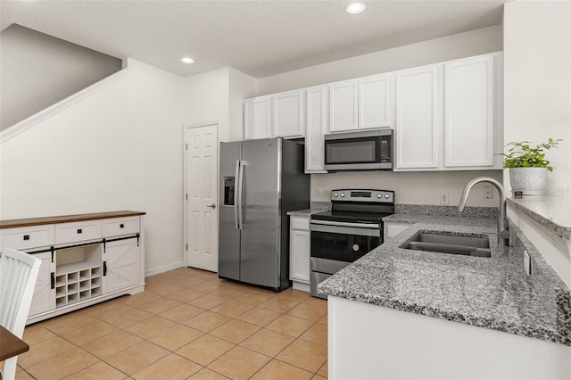 kitchen with white cabinetry, sink, stainless steel appliances, light stone counters, and light tile patterned flooring