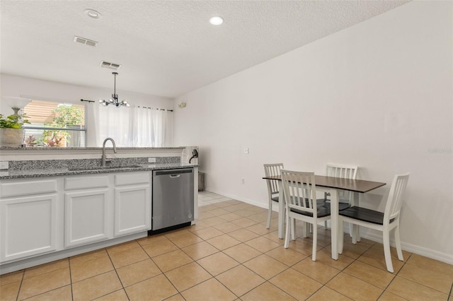 kitchen featuring stainless steel dishwasher, sink, a notable chandelier, white cabinets, and hanging light fixtures