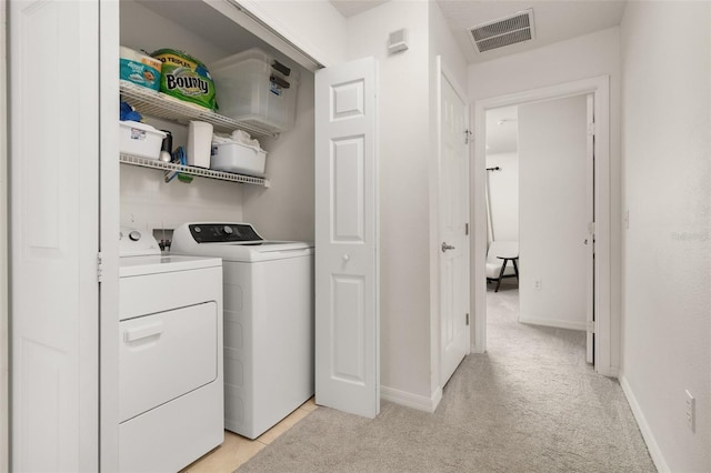 laundry area with separate washer and dryer and light carpet