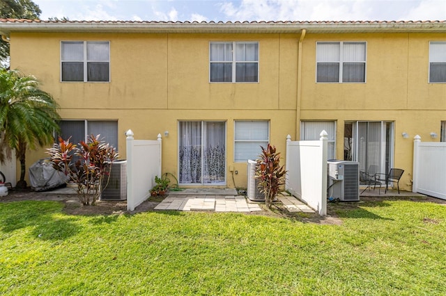 rear view of property featuring a lawn and central air condition unit