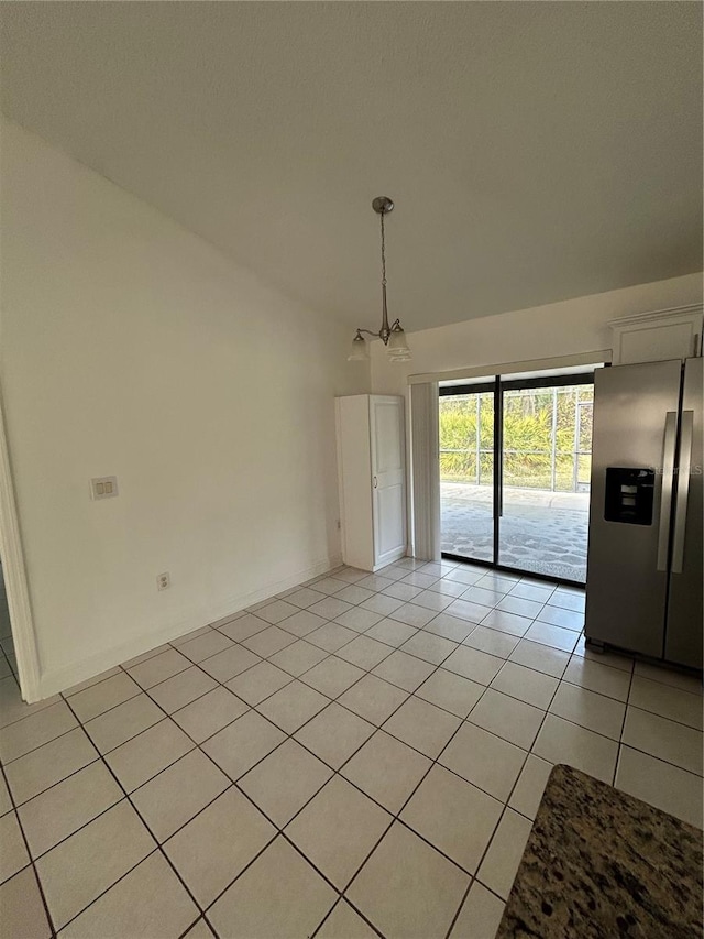 unfurnished dining area featuring light tile patterned flooring and an inviting chandelier