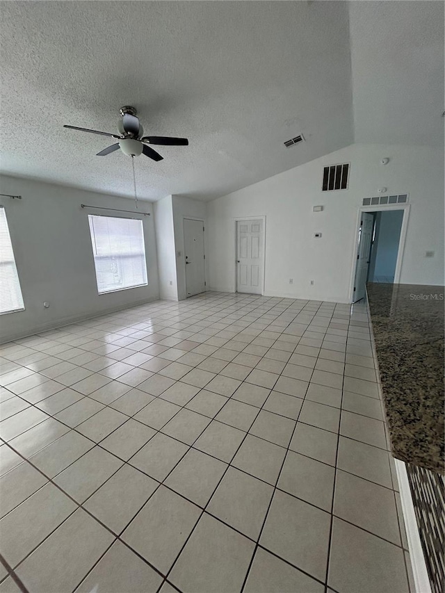 unfurnished room featuring vaulted ceiling, ceiling fan, light tile patterned flooring, and a textured ceiling