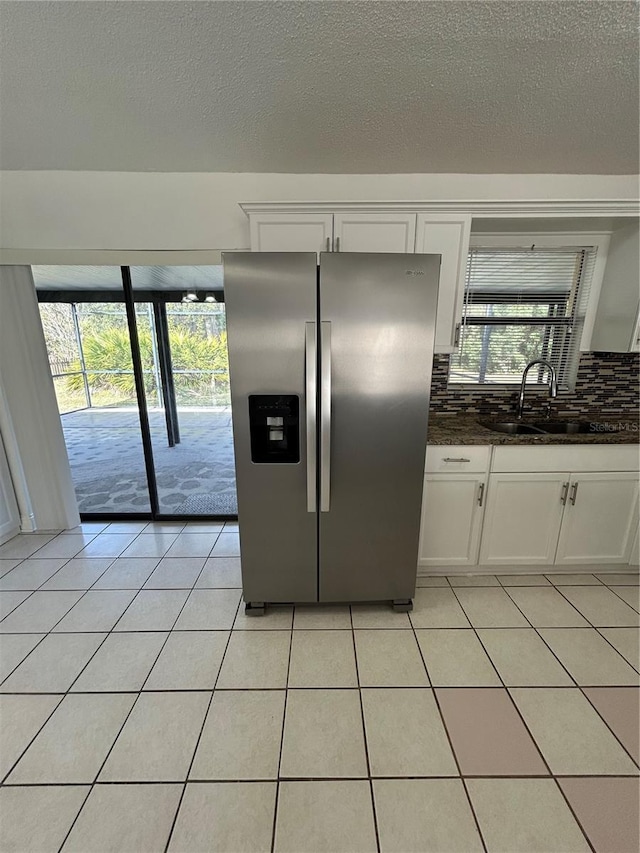 kitchen featuring white cabinetry, sink, stainless steel refrigerator with ice dispenser, backsplash, and light tile patterned floors